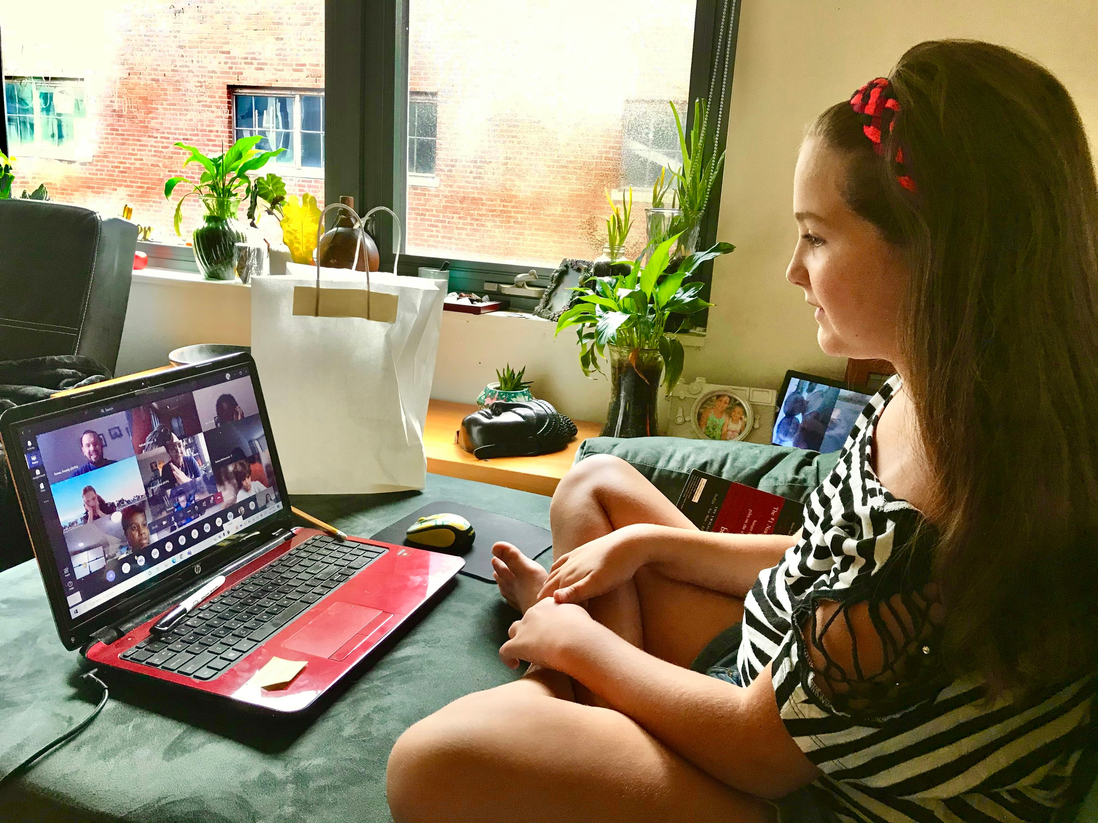 Young girl enthusiastically learning Spanish remotely on her laptop, interacting with native-speaking Spanish teachers